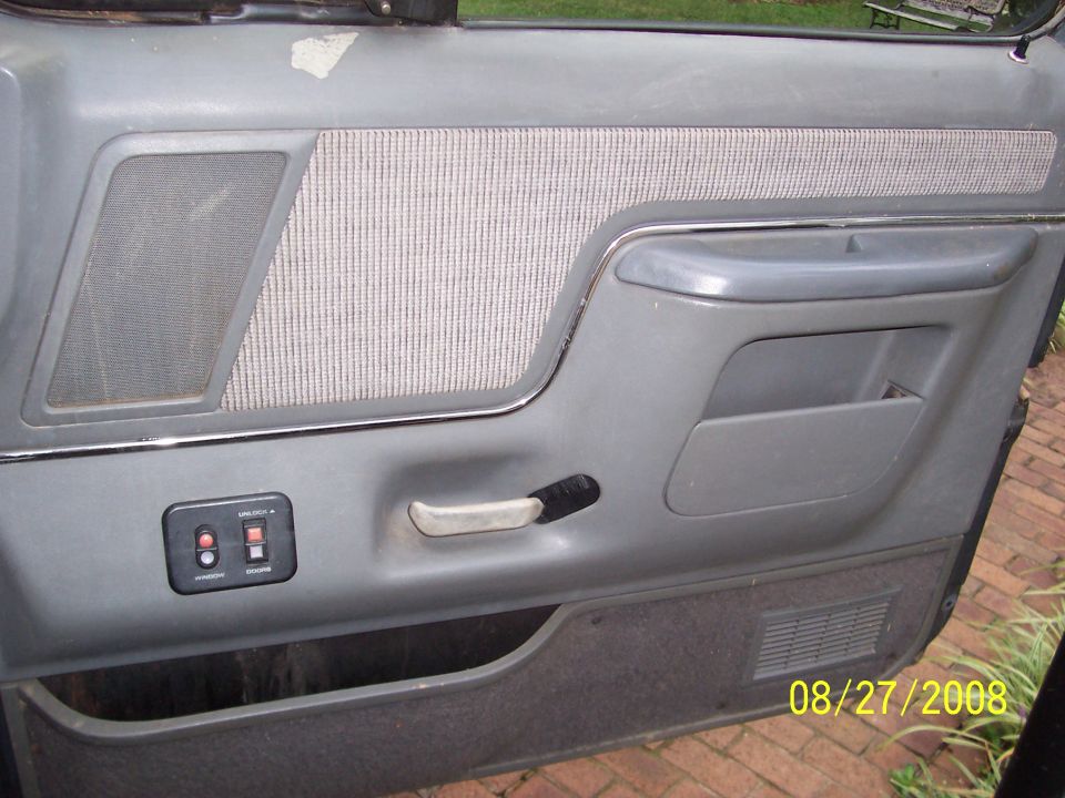 gray interior door panel with fabric insert, speaker grille, and power window controls