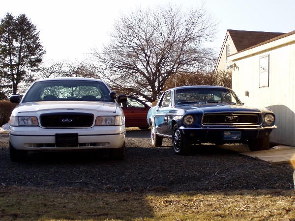 1968 Ford Mustang parked next to a white sedan