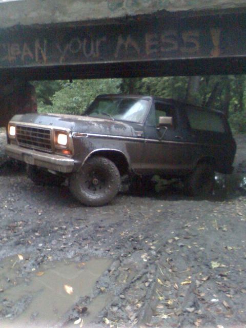 1979 Ford Bronco - This Bronco is stuck in the mud under a bridge that has graffiti on it.