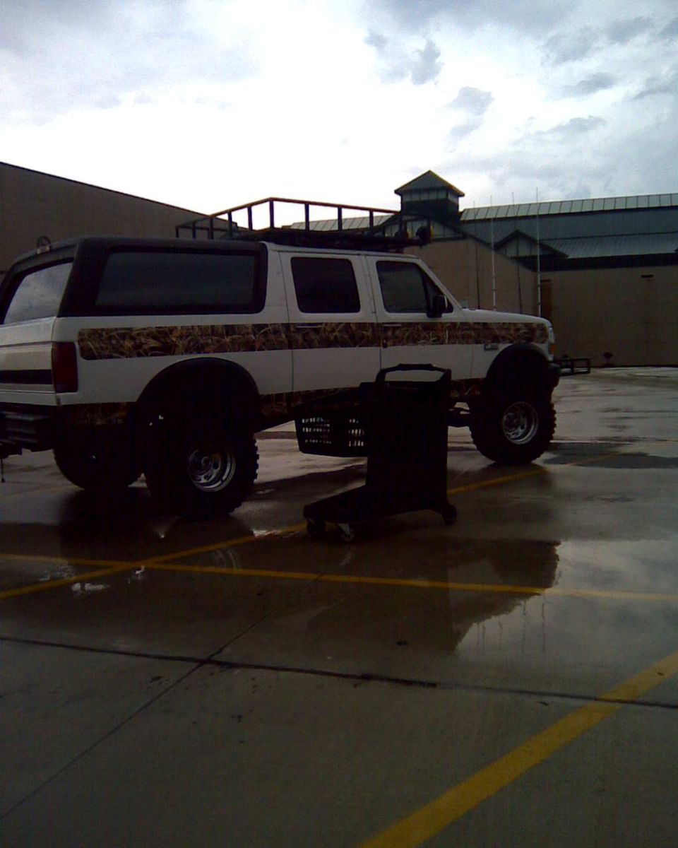White lifted two-door SUV with camo graphics on wet parking lot