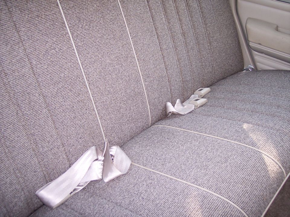Gray tweed bench seat interior with beige lap belts and buckles