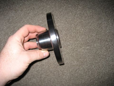 1995 Ford Bronco - A person holds a metal flange part, likely for automotive use, against a carpeted background.