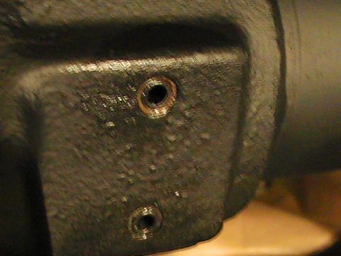 1992 Ford Bronco - A close-up view of a dark metal component two threaded bolt holes, likely part of a vehicle's mechanical system.