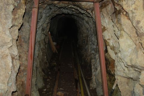 1997 Ford F-250 - A dark mine tunnel with tracks runs into the distance, supported by rough-hewn rock and metal beams.