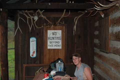 1997 Ford F-250 - A man sits in a rustic cabin decorated with deer antlers and a sign prohibiting hunting beyond this point.