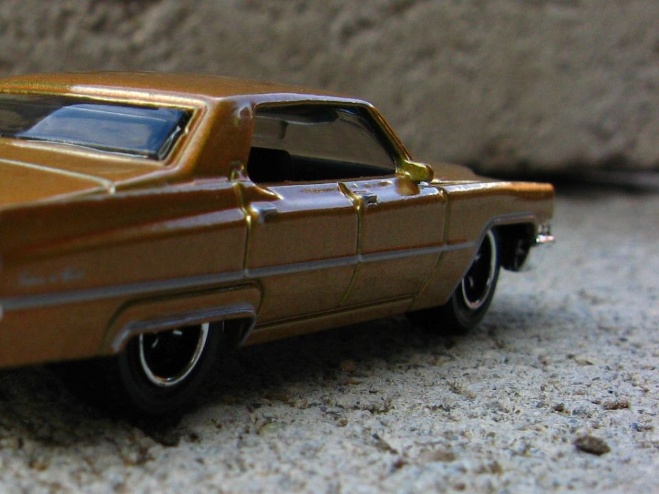 Close-up rear quarter of bronze die-cast 1960s hardtop model on concrete