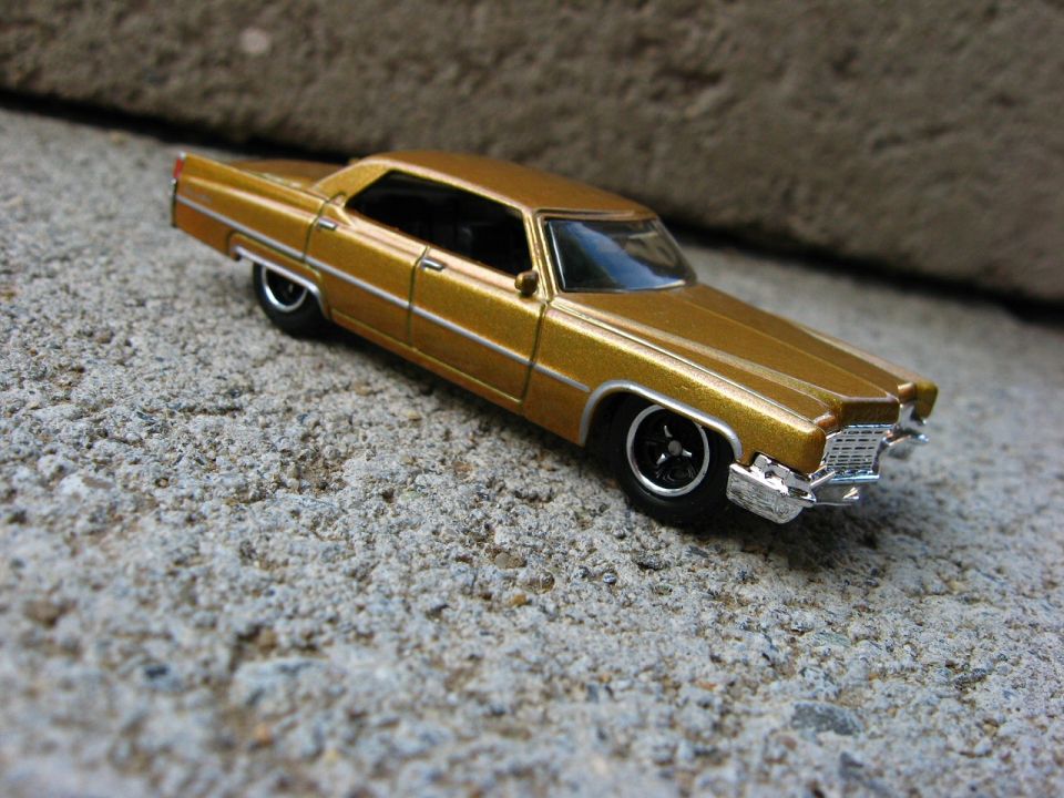 Gold metallic die-cast Cadillac four-door hardtop model on concrete