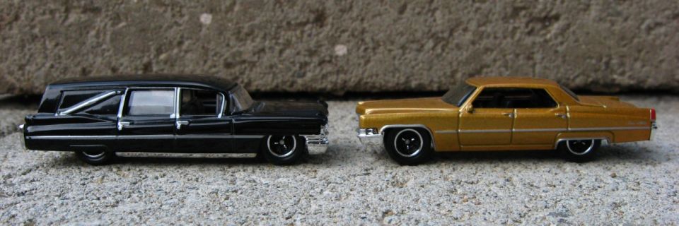 Side view of black die-cast Cadillac hearse and gold Cadillac sedan models