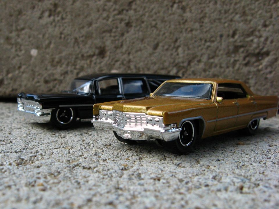 Gold die-cast 1960s Cadillac model in front of a black hearse model