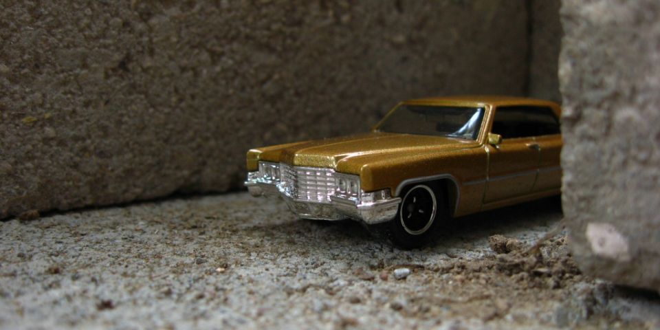Gold die-cast Cadillac model at low angle in a concrete block corner