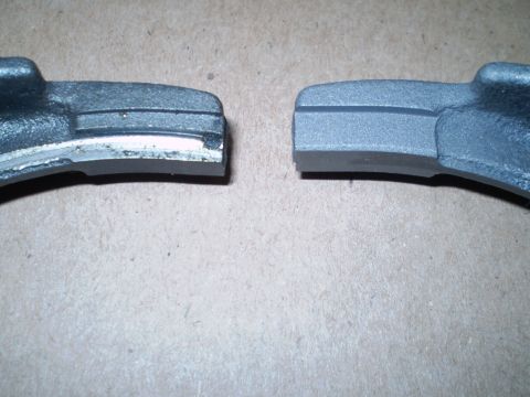1995 Ford F-150 - Comparison of two curved cast-metal components on cardboard, left part worn and right part fresh.