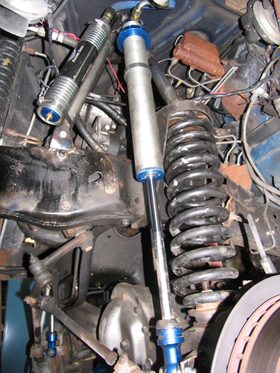 Close-up of front suspension with coil springs and shock absorbers. One shock has 'Extreme Shock' text