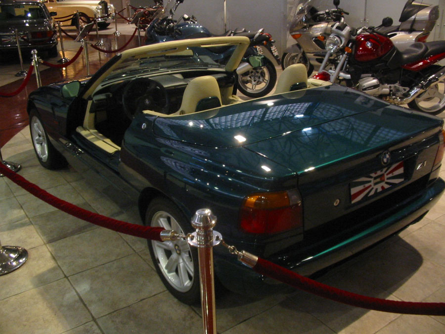 Green BMW Z3 convertible with tan interior, parked indoors with motorcycles behind it