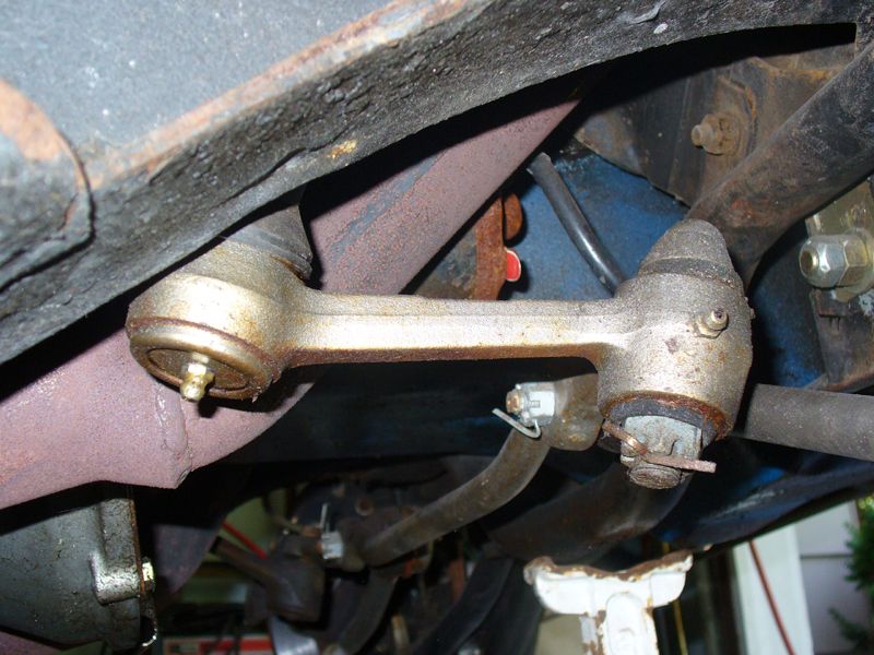 Undercarriage view of rusty suspension parts and exhaust manifold