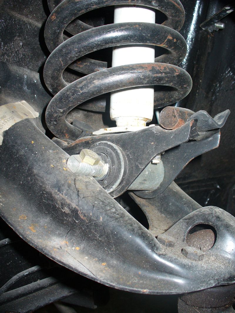 Front coil spring and white shock on black lower control arm with pivot bolt, underside