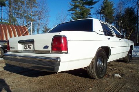 1991 Ford Crown Victoria LTD - Rear view of a white sedan with a chrome bumper and tinted windows.