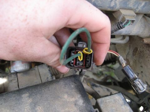 1995 Ford Bronco - A hand manipulates a wiring harness connector, showing internal pins and attached wires.