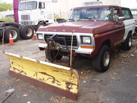 1979 Ford Bronco - A weathered Ford Bronco, likely from the late 1970s, is equipped with a front-mounted snow plow.