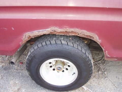 1979 Ford Bronco - Rust damage is visible around the rear wheel well of this red vehicle, which has a steel radial tire.