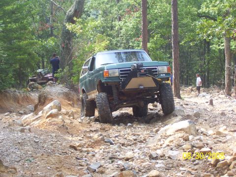 1978 Ford Bronco - A green SUV tackles a challenging off-road course with another vehicle visible in the background.