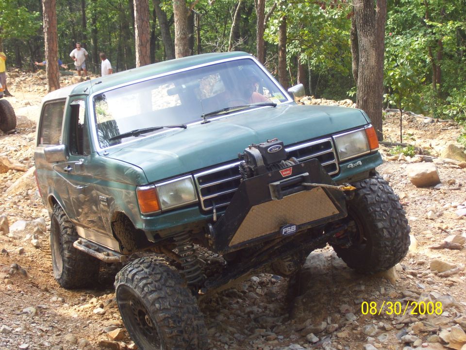 Green SUV with winch and off-road tires on rocky terrain