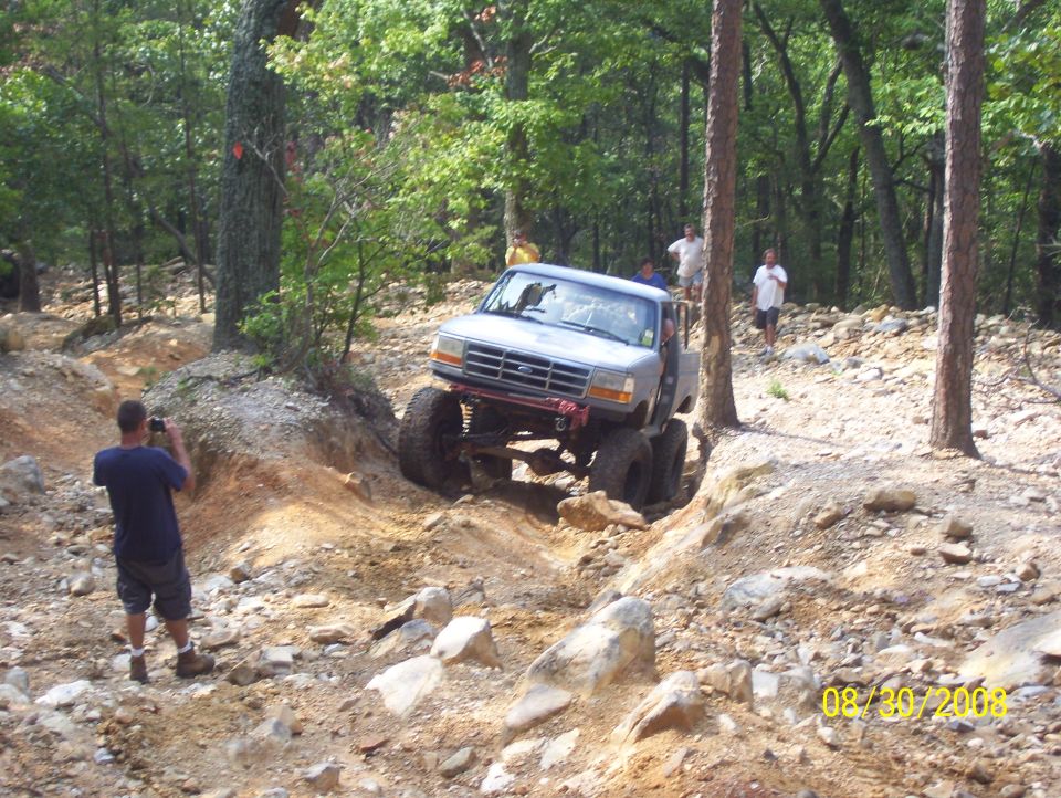 Modified pickup truck with large tires climbing a steep, rocky trail. Date stamp reads 08/30/2008