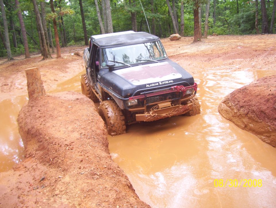 Off-road vehicle with "ALASKAN EXTREME" decal stuck in a mud pit