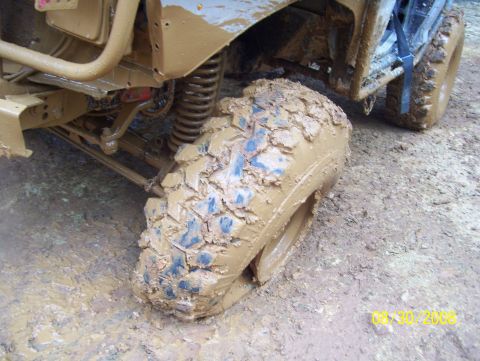 1978 Ford Bronco - A vehicle is stuck deep in mud, with its tire and suspension heavily covered.