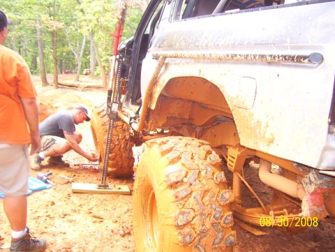 1978 Ford Bronco - A muddy 1978 Ford Bronco is being worked on with a jack in an outdoor setting.