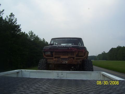 1978 Ford Bronco - A heavily modified 1978 Ford Bronco is seen from the perspective of a pickup truck bed on a cloudy day.