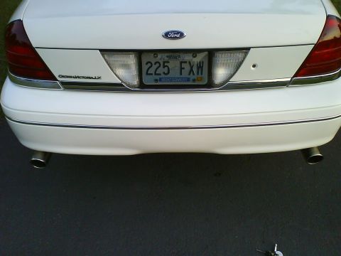 2003 Ford Crown Victoria - The rear of a white 2003 Ford Crown Victoria, showing the taillights, Ford emblem, and license plate.