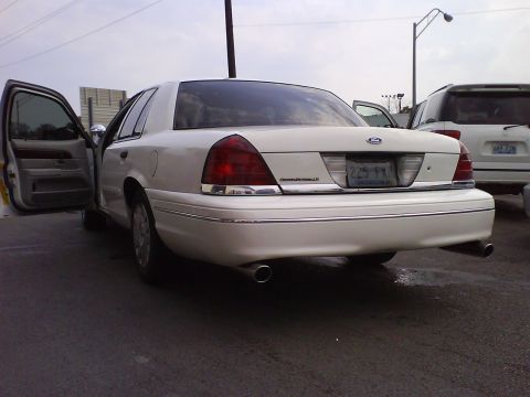 2003 Ford Crown Victoria - Rear view of a white 2003 Ford Crown Victoria, showing its license plate and open doors.