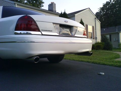 2003 Ford Crown Victoria - The rear of a white Ford Crown Victoria is shown parked in a driveway with a house in the background.