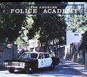 1991 Ford LTD Crown Victoria - A black-and-white police cruiser with a roof light bar parked on a driveway beneath an arched sign reading "LOS ANGELES POLICE ACADEMY," fr…