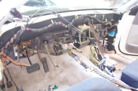 1996 Ford Crown Victoria - The interior of a vehicle shows exposed wiring and disassembled dashboard components, with pedals visible on the floor.