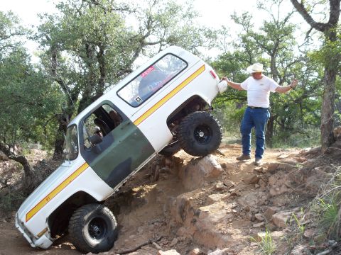 1996 Ford Bronco - A man watches as a modified SUV navigates a steep, rocky trail.