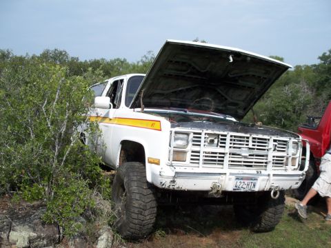 1996 Ford Bronco - White Chevrolet K5 Blazer with hood open, parked off-road with a red vehicle nearby.