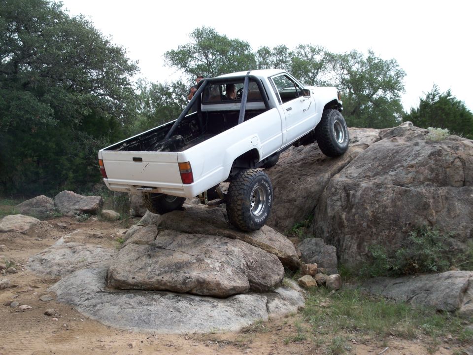 White Toyota pickup truck climbing over large rocks on a trail