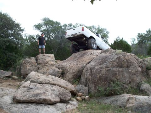 1996 Ford Bronco - A man stands on rocks watching a white pickup truck navigate a challenging rocky terrain.