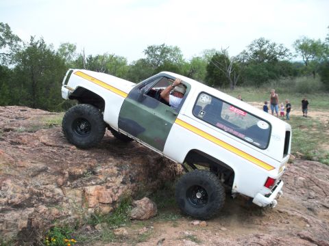 1996 Ford Bronco - This lifted SUV with a two-tone paint job is navigating a rocky terrain.