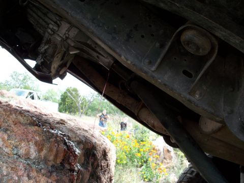 1996 Ford Bronco - A low-angle shot reveals the underside of a vehicle's frame and drivetrain, with another vehicle parked in the background.