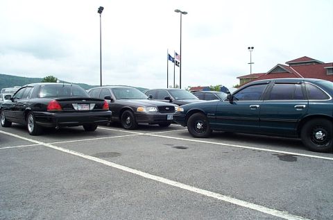 1991 Ford LTD Crown Victoria - Several Ford Crown Victoria sedans are parked in a lot under an overcast sky.