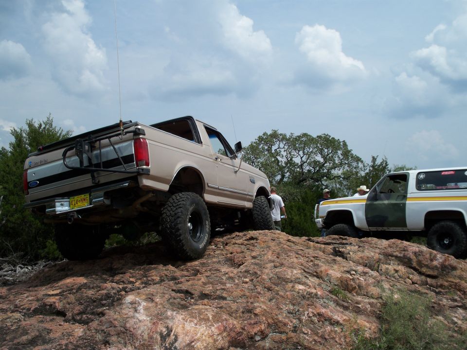 Tan Ford Bronco and white Chevrolet K5 Blazer on rocky hill