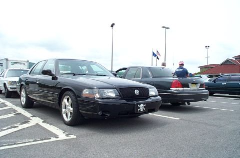 1991 Ford LTD Crown Victoria - A black sedan with a custom license plate is parked in a lot with other vehicles.