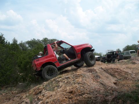 1996 Ford Bronco - Multiple off-road vehicles navigate a challenging rocky terrain under a cloudy sky.