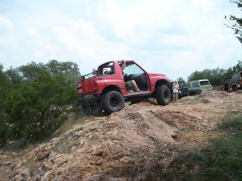 1996 Ford Bronco - A group of off-road vehicles navigate a rocky trail under a cloudy sky.