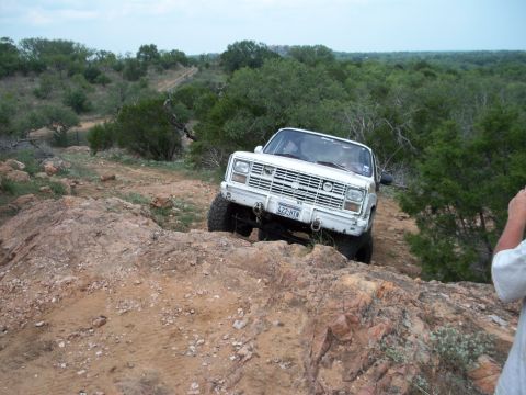 1996 Ford Bronco - White off-road SUV with a distinctive grille and bumper is shown traversing a rocky, off-road path.