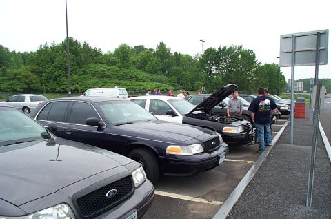 1991 Ford LTD Crown Victoria - Multiple Ford Crown Victoria police cars are parked in a lot, with one car's hood open.
