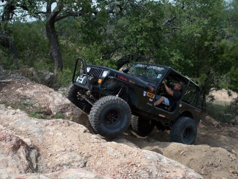 1996 Ford Bronco - A black Jeep Wrangler navigates a challenging rocky terrain, displaying "DIXCO OFFROAD" on its windshield banner.