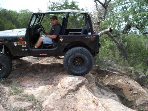 1996 Ford Bronco - A black Jeep Wrangler navigates a rocky trail, with a driver behind the wheel.